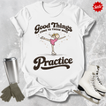 White t-shirt with a graphic and text, surrounded by ice skates, gloves, and a tumbler on a textured surface.