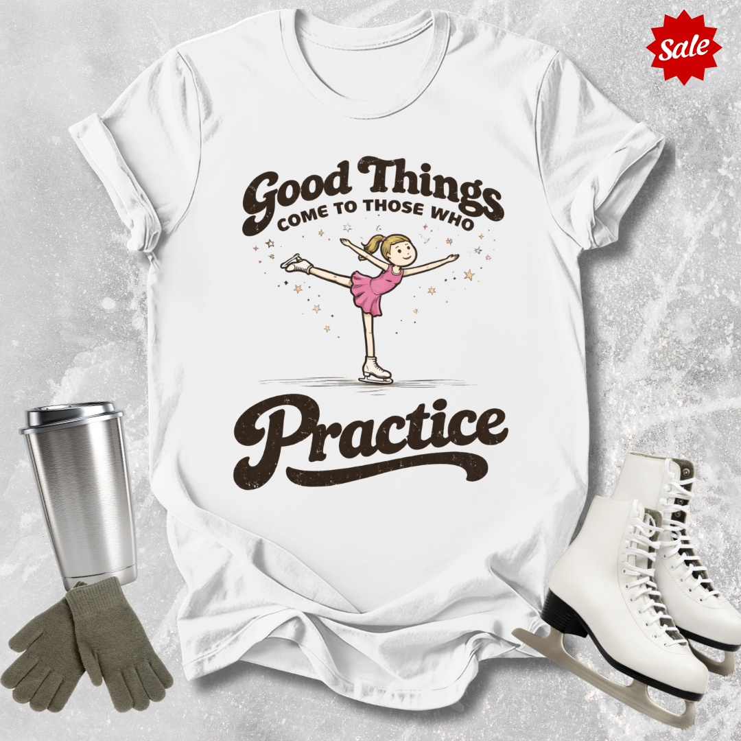 White t-shirt with a graphic and text, surrounded by ice skates, gloves, and a tumbler on a textured surface.