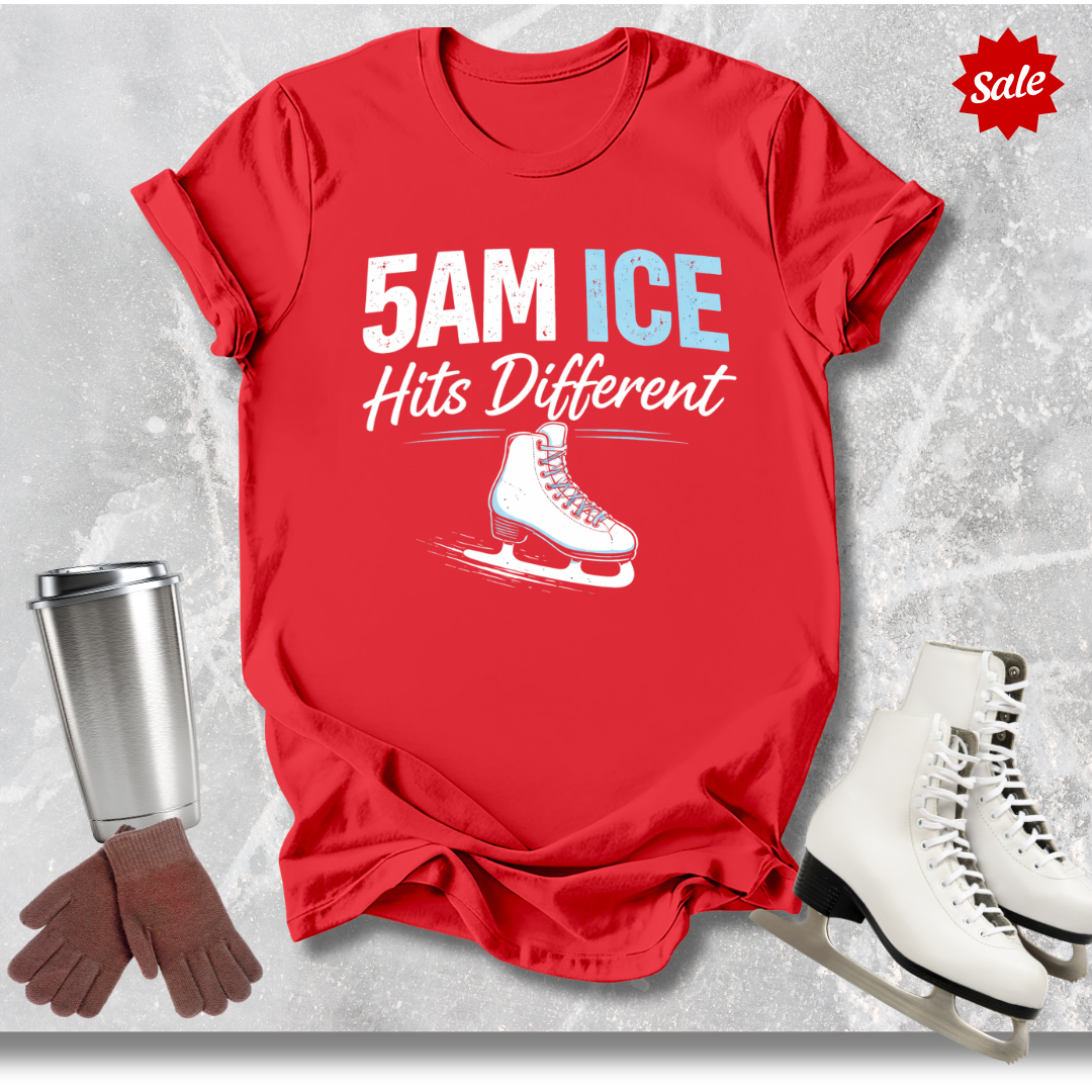 Red t-shirt with '5AM ICE Hits Different' text and ice skate graphic, surrounded by ice skates, gloves, and a tumbler on a gray background.