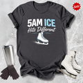 Black t-shirt with '5AM ICE Hits Different' text and ice skate graphic, surrounded by ice skates and a tumbler on a textured gray background.