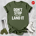 Green t-shirt with motivational quote, silver tumbler, green gloves, and white skates on a textured gray background.