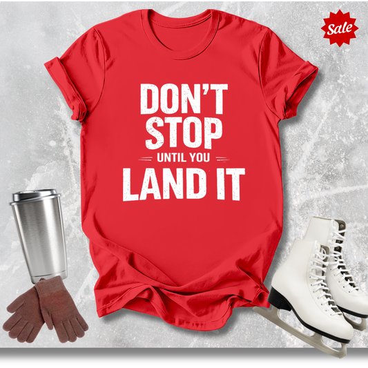 Red t-shirt with motivational quote, next to a cup, gloves, and skates on a textured gray background.