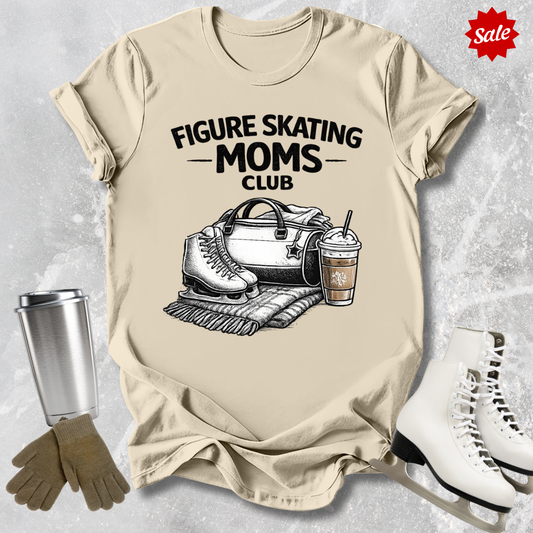 Beige t-shirt with 'Figure Skating Moms Club' graphic, surrounded by ice skates, gloves, and a cup on a textured surface.