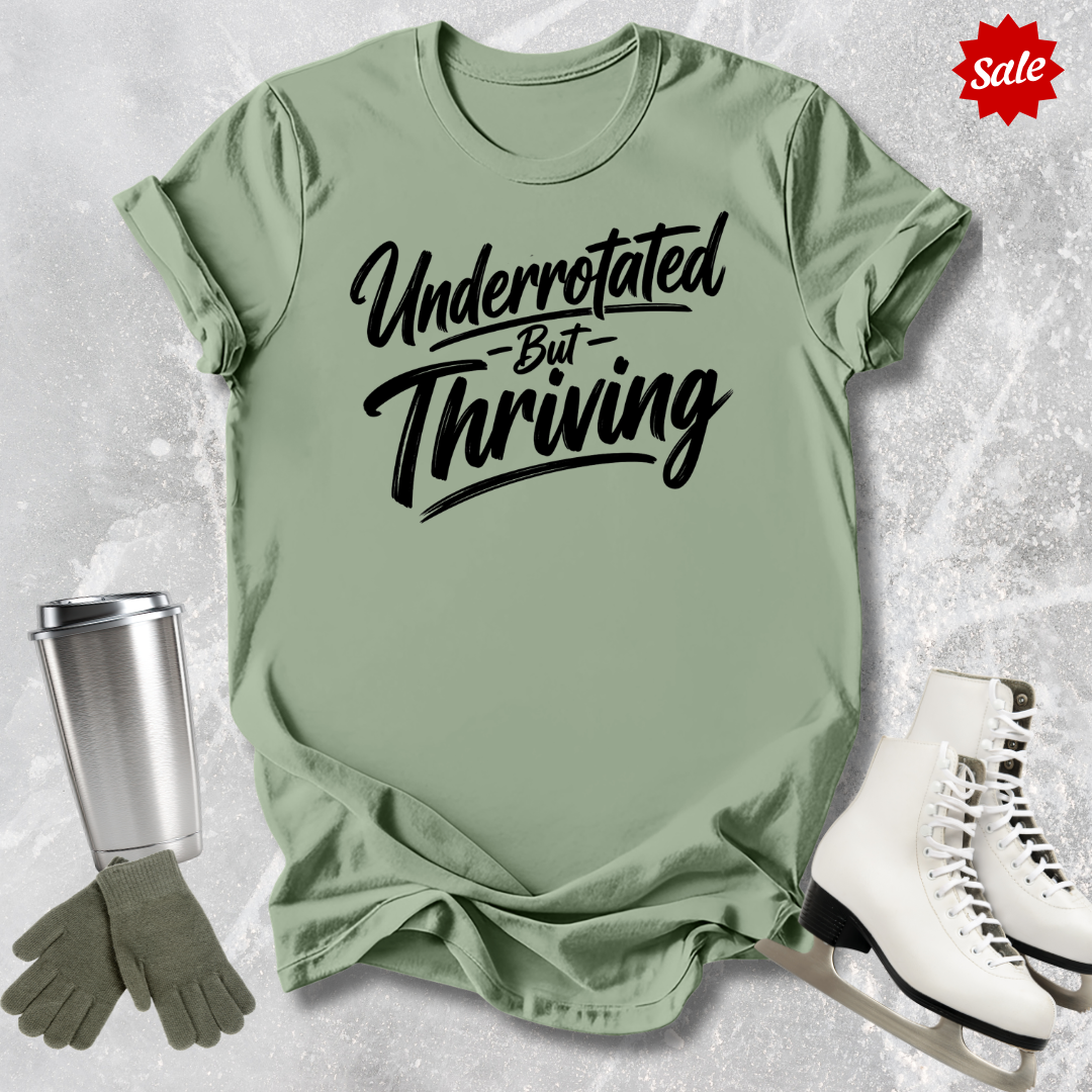 Green t-shirt with 'Underrotated But Thriving' text, silver tumbler, green gloves, and white sneakers on a textured surface.