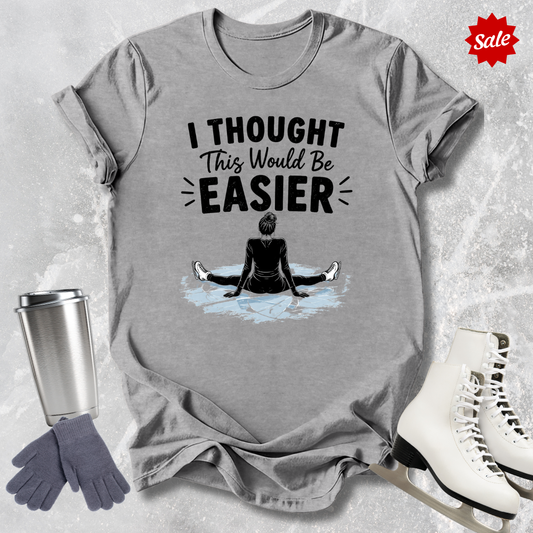 Gray t-shirt with 'I Thought This Would Be Easier' graphic and accessories on a textured surface.