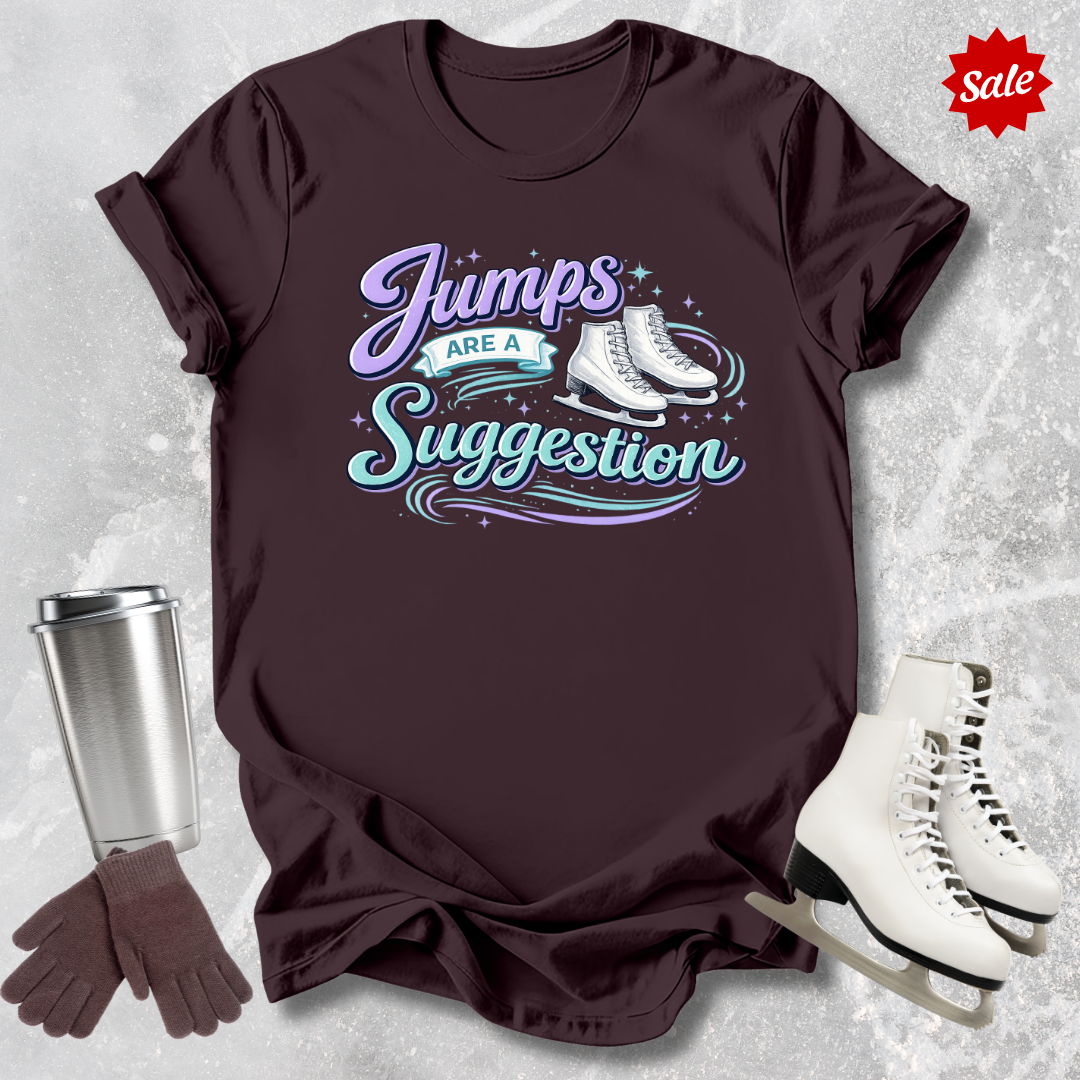 Brown t-shirt with 'Jumps are a Suggestion' text, silver tumbler, brown gloves, and white ice skates on a textured gray background.