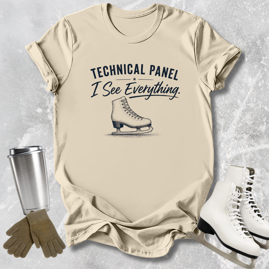 Beige t-shirt with ice skate graphic and text, surrounded by ice skates and a tumbler on a textured surface.