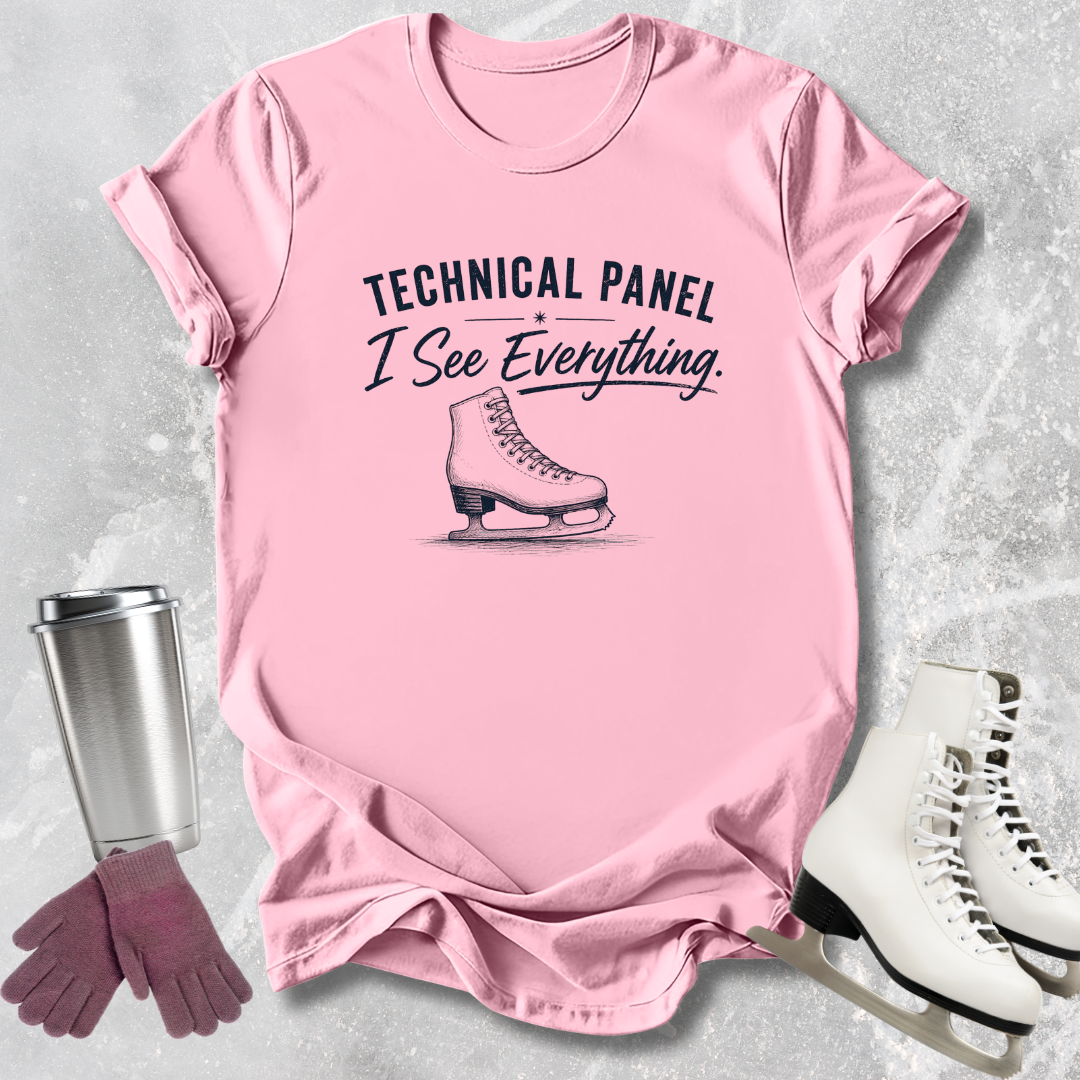 Pink t-shirt with ice skate graphic and text, surrounded by ice skates and a tumbler on a textured surface.
