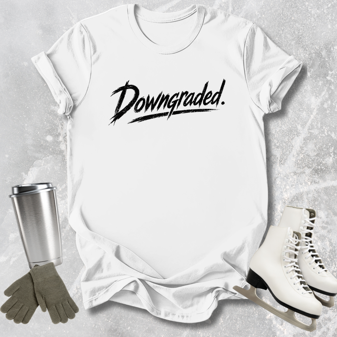 White t-shirt with 'Downgraded' text, silver tumbler, green gloves, and white skates on a gray textured background