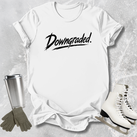 White t-shirt with 'Downgraded' text, silver tumbler, green gloves, and white skates on a gray textured background