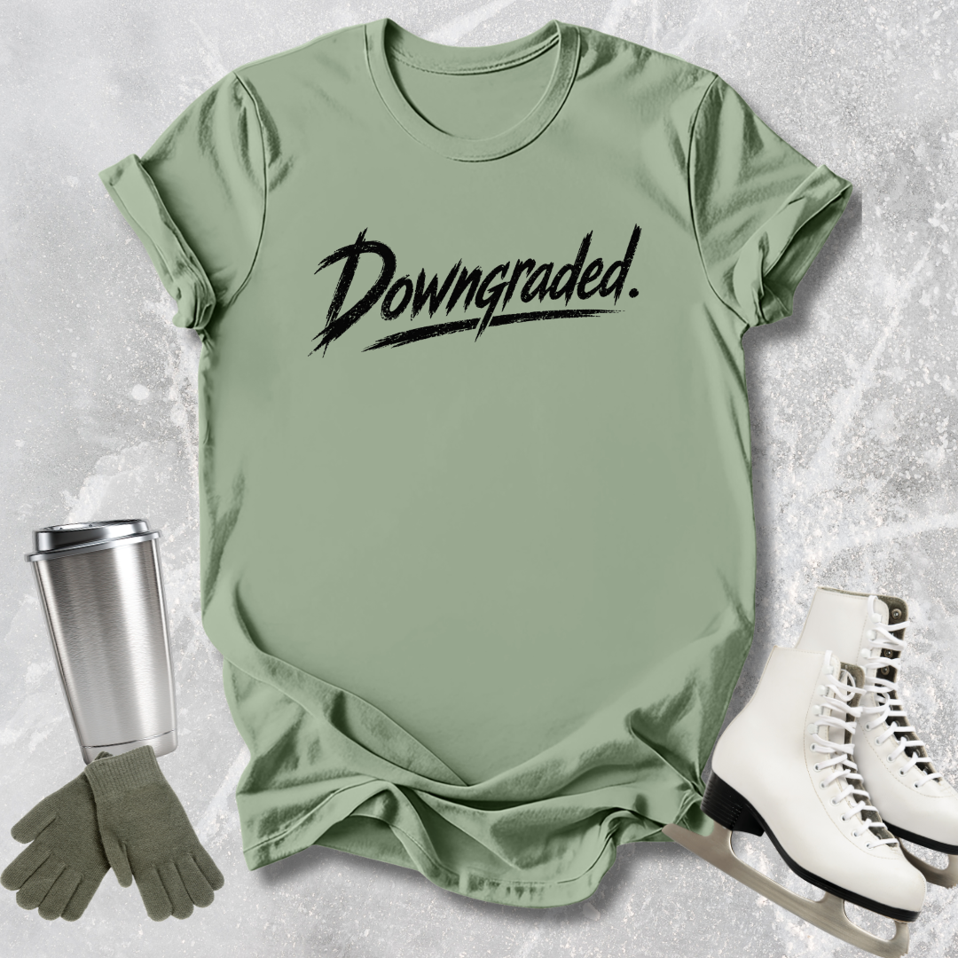 Green t-shirt with 'Downgraded' text, gloves, and white shoes on a textured surface