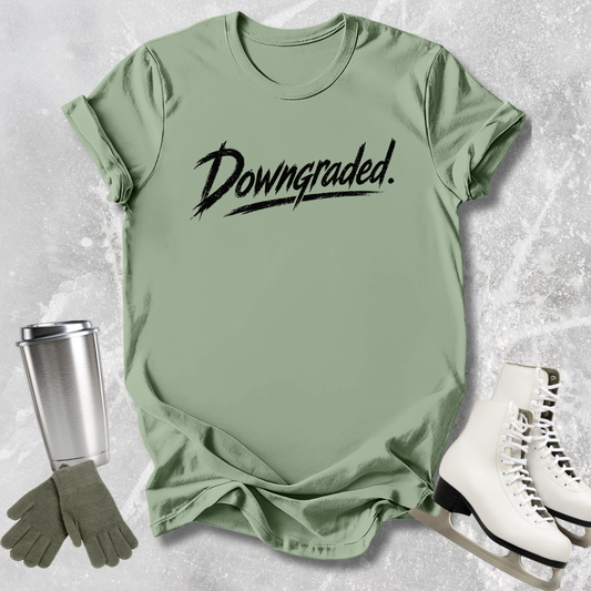 Green t-shirt with 'Downgraded' text, gloves, and white shoes on a textured surface