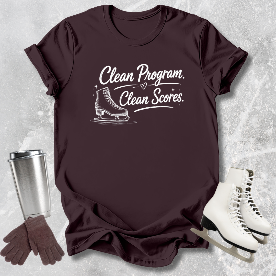 Brown  t-shirt with 'Clean Program, Clean Scores' text and ice skate graphic on a textured surface with ice skates and gloves.