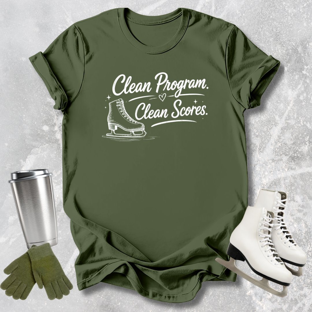 Green t-shirt with 'Clean Program, Clean Scores' text and ice skate graphic, next to a silver tumbler, green gloves, and white ice skates on a textured gray background.