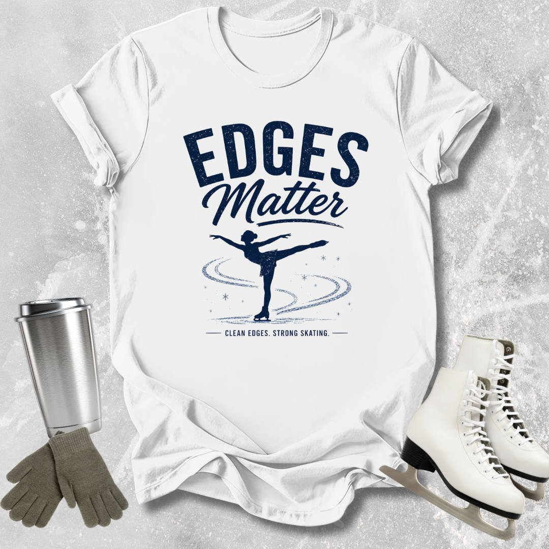 White t-shirt with 'Edges Matter' graphic on a textured surface with ice skates and gloves.