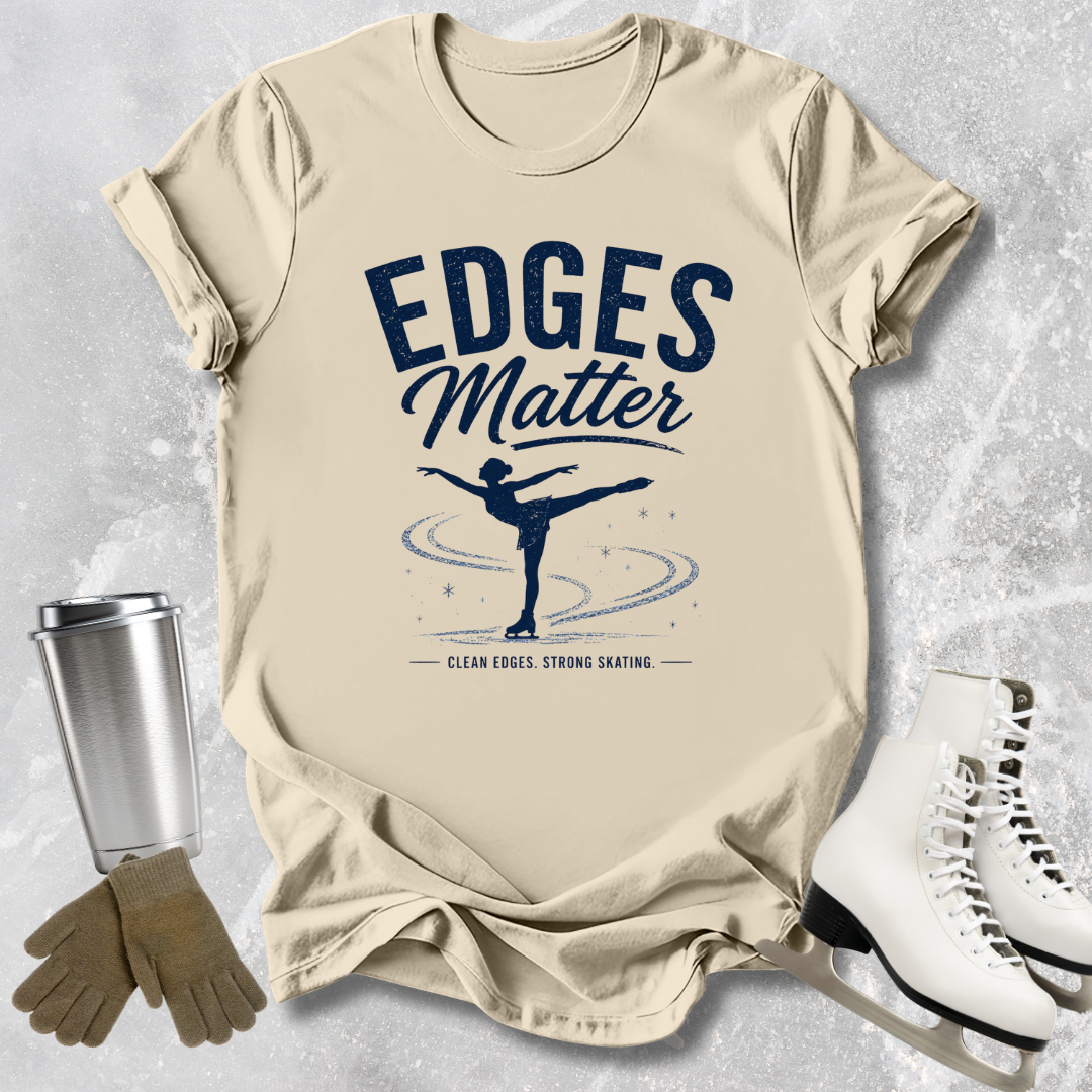 Beige t-shirt with 'Edges Matter' graphic and ice skates on a textured surface