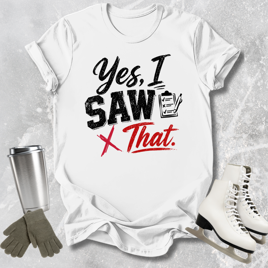White t-shirt with 'Yes, I Saw That' text, next to a silver tumbler, gray gloves, and white skates on a textured gray background.
