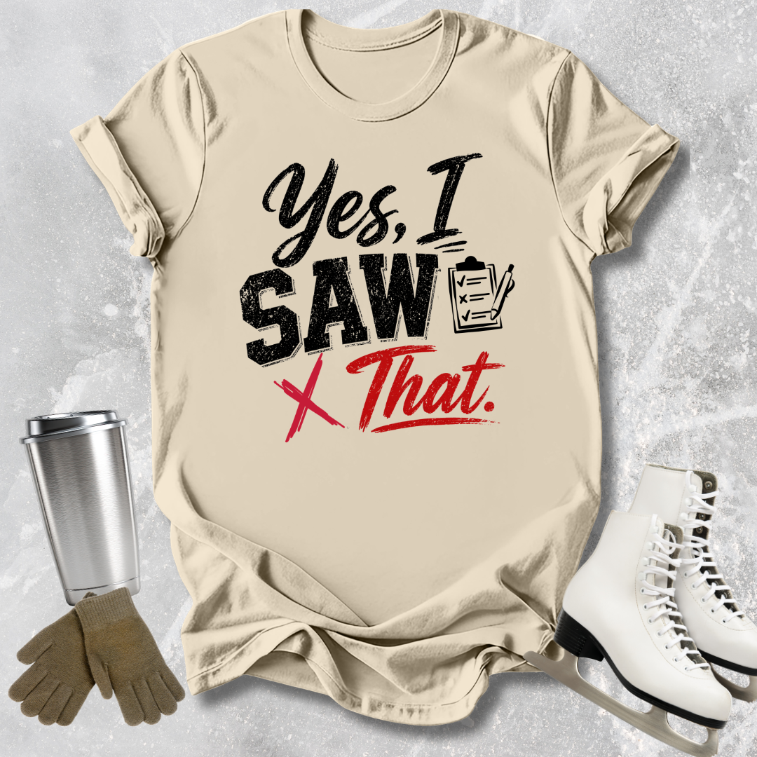 Beige t-shirt with humorous text design, placed on a textured surface with accessories like a tumbler, gloves, and skates.