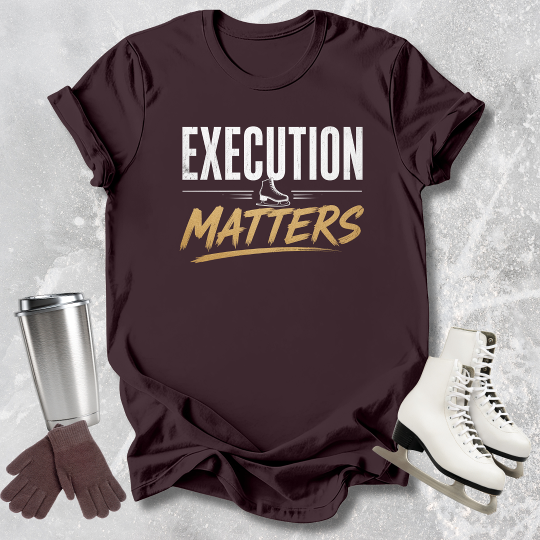 Brown t-shirt with 'Execution Matters' text, silver tumbler, brown gloves, and white skates on a textured gray background