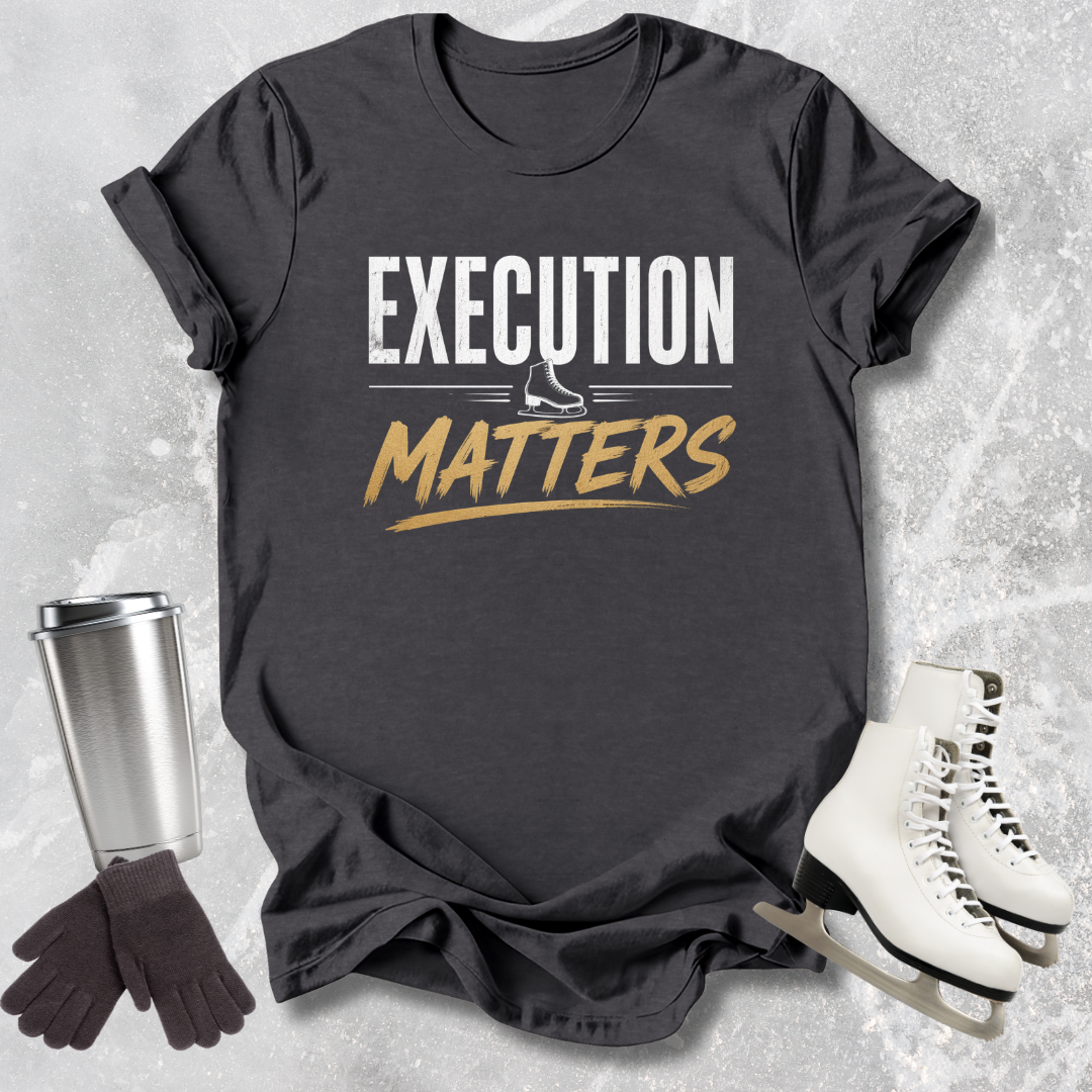 Black t-shirt with 'Execution Matters' text, silver tumbler, black gloves, and white skates on a textured surface.