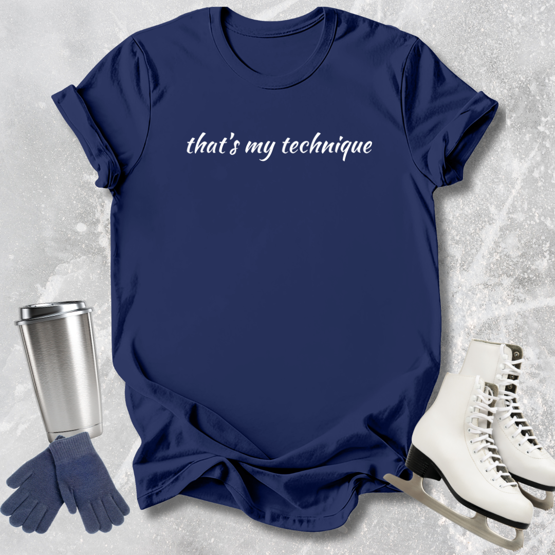 Navy blue t-shirt with 'that's my technique' text, next to a silver tumbler, gloves, and white skates on a textured gray background.
