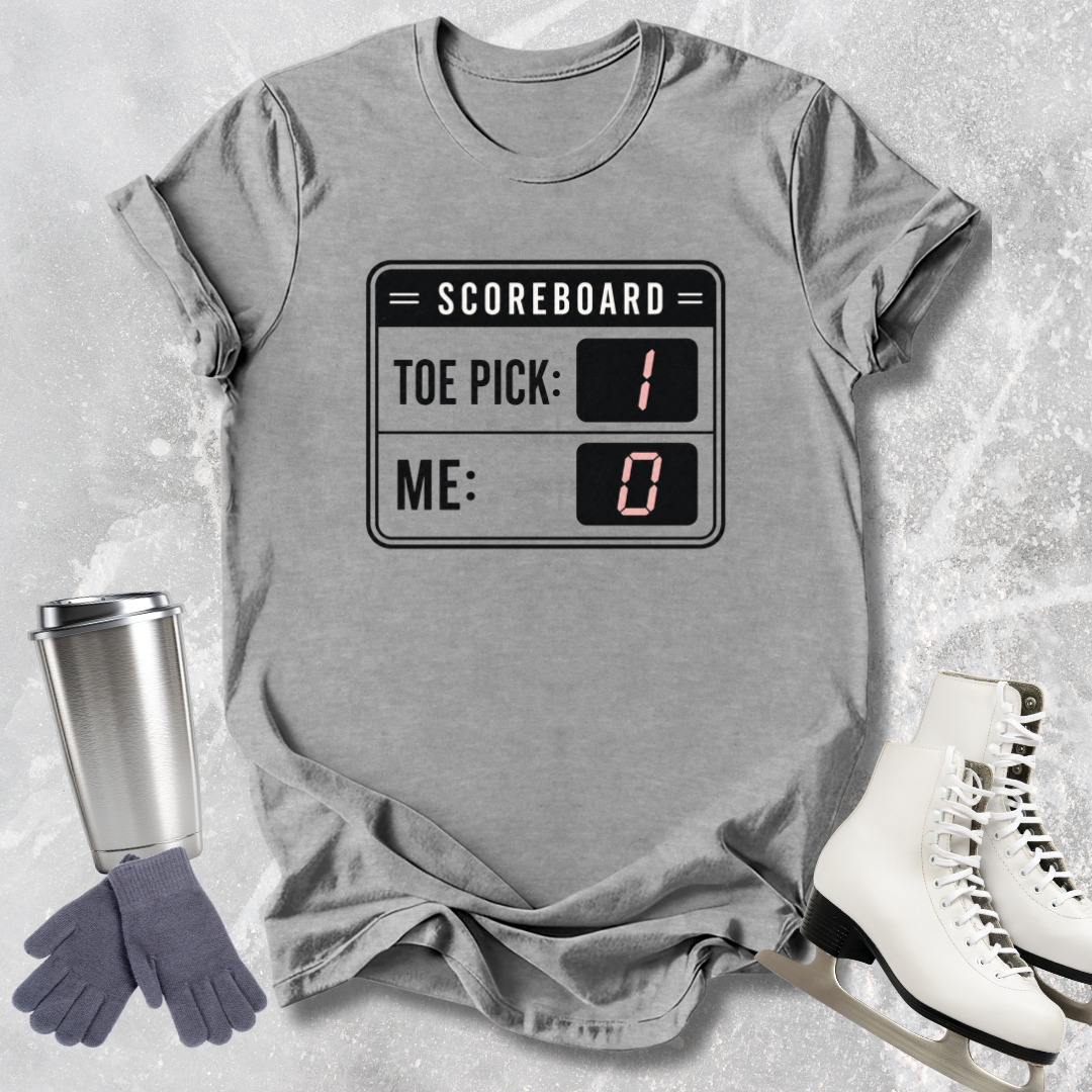 Gray t-shirt with scoreboard design, next to a travel mug, gloves, and skates on a textured surface.