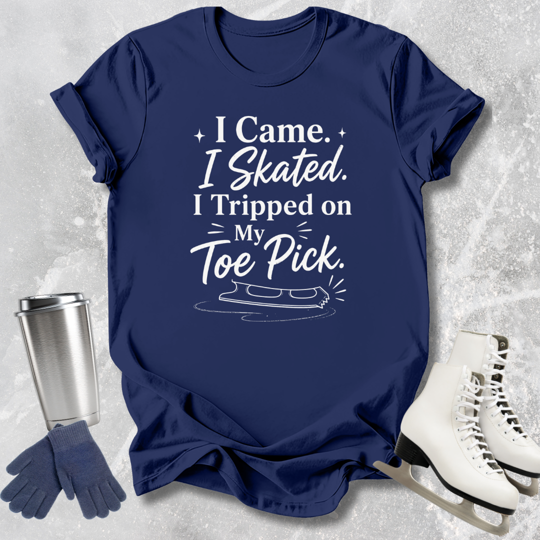 Navy blue t-shirt with 'I came I skated. I tripped on my toe pick' text and ice skate graphic on a textured gray background.
