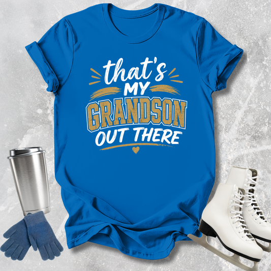 Blue t-shirt with 'That's my grandson out there' text, next to a silver tumbler, blue gloves, and white skates on a textured gray background.