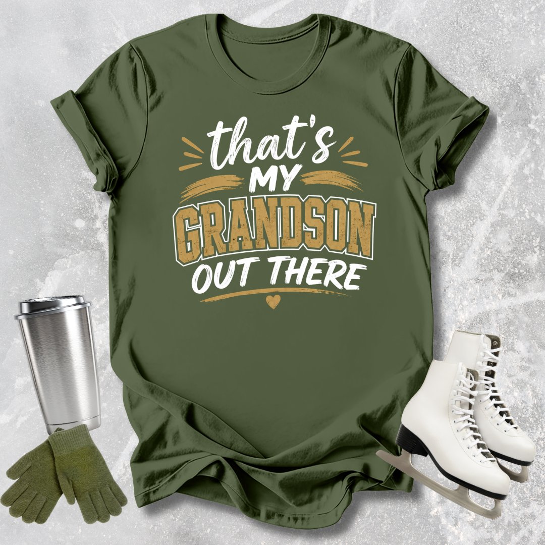 Green t-shirt with 'That's my grandson out there' text, next to a silver tumbler, green gloves, and white skates on a textured gray background.
