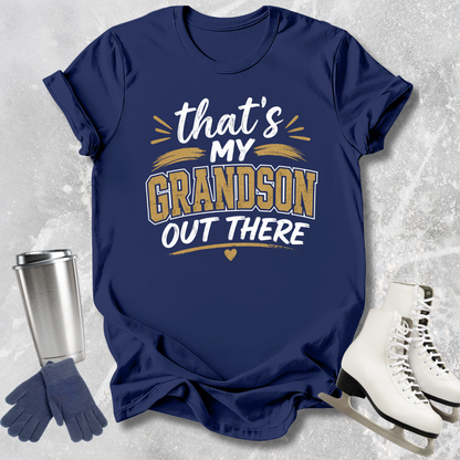 Navy blue t-shirt with 'That's my grandson out there' text, next to a silver tumbler, gloves, and white skates on a textured gray background.