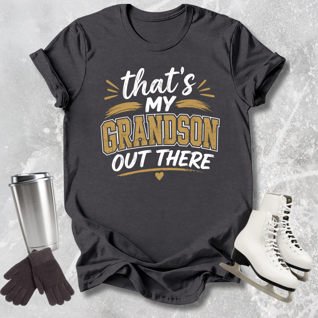 Black t-shirt with 'That's my grandson out there' text, next to a silver tumbler, black gloves, and white skates on a textured gray background.