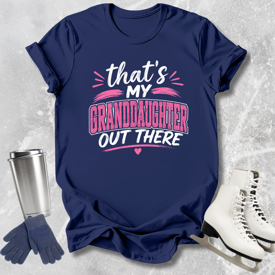 Navy blue t-shirt with 'That's my granddaughter out there' text, next to a silver tumbler, gloves, and white skates on a textured gray background.