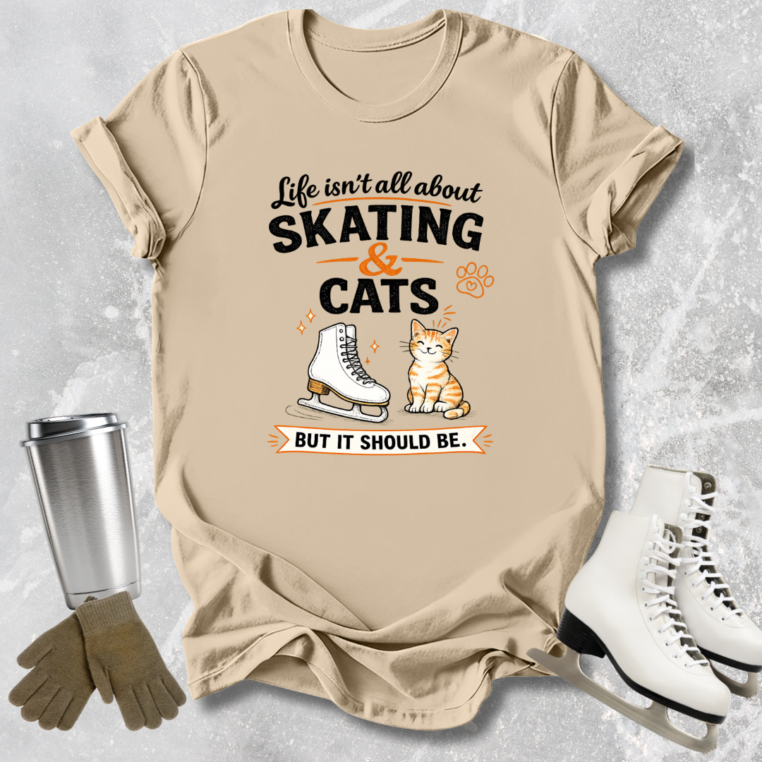 Beige t-shirt with skating and cats graphic and text on a textured surface with ice skates and gloves.