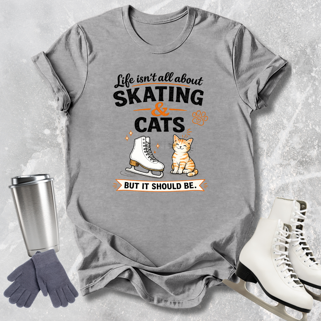 Gray t-shirt with skating and cats graphic and text, placed on a textured surface with ice skates and gloves.