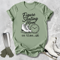 Green t-shirt with figure skating mom graphic and accessories on a textured surface