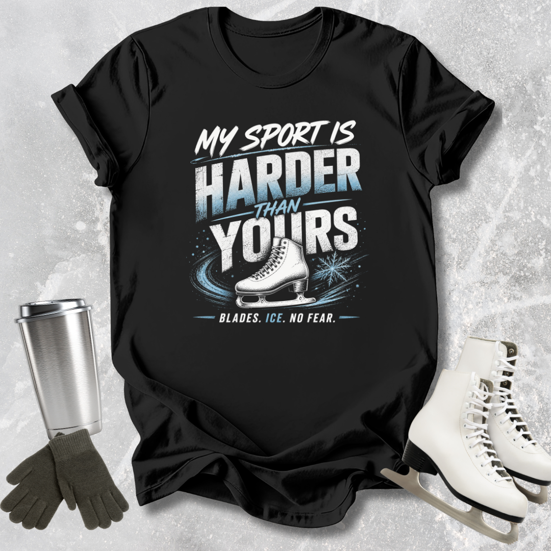 Black t-shirt with ice skating graphic and text, surrounded by ice skates, gloves, and a tumbler on a textured gray background.