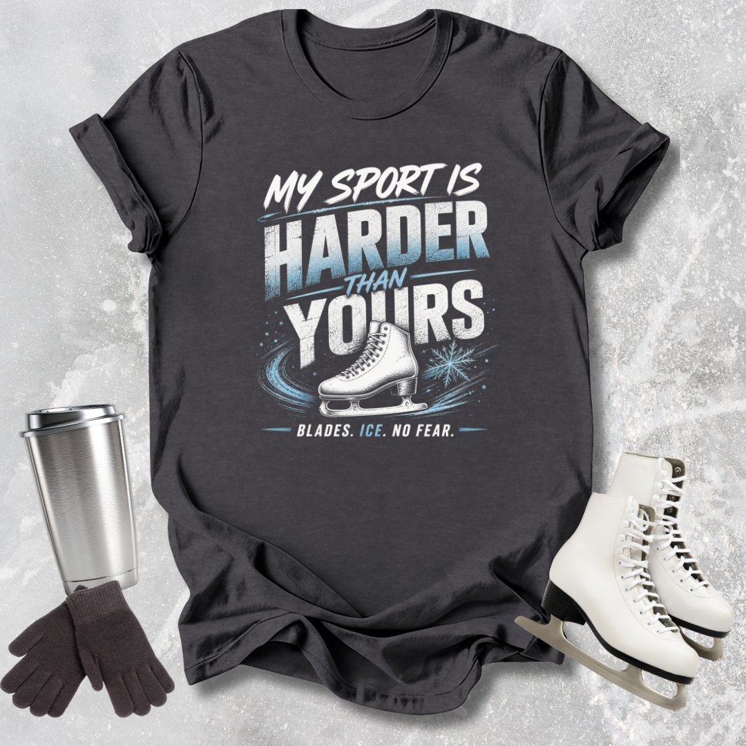 Black t-shirt with ice skating design and text, surrounded by ice skates, gloves, and a tumbler on a textured gray background.