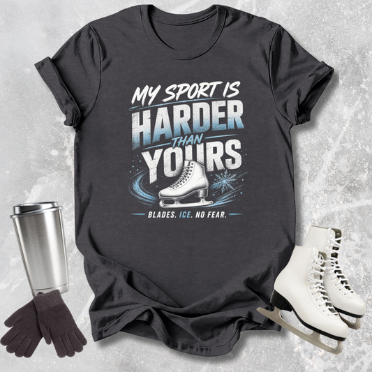 Black t-shirt with ice skating design and text, surrounded by ice skates, gloves, and a tumbler on a textured gray background.