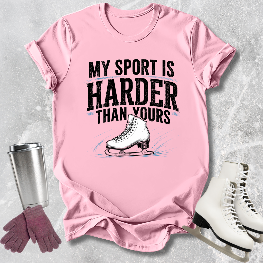 Pink t-shirt with 'My sport is harder than yours' text and ice skate graphic, surrounded by ice skates and a tumbler.