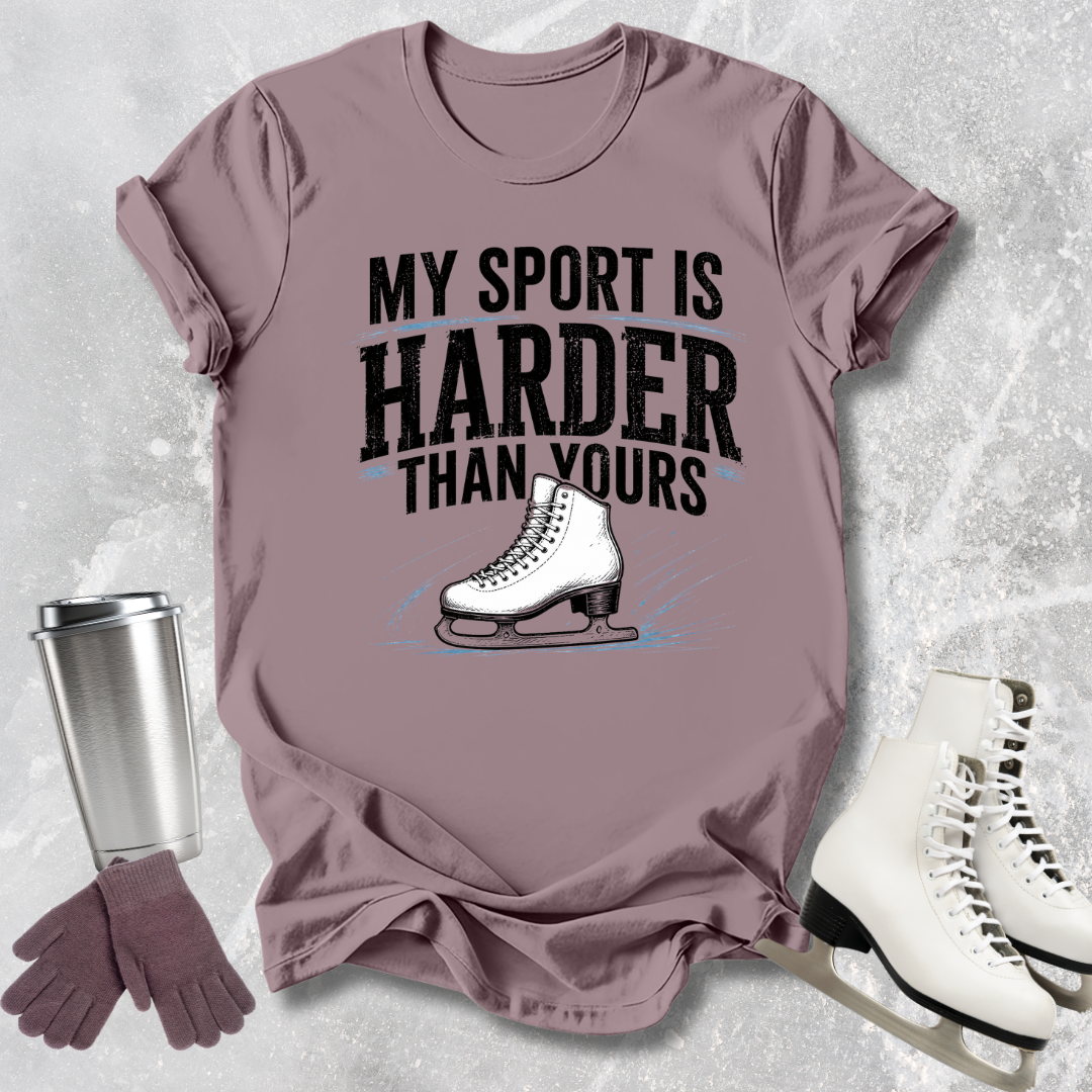 Purple t-shirt with 'My sport is harder than yours' text and ice skate graphic, surrounded by ice skates and a tumbler.