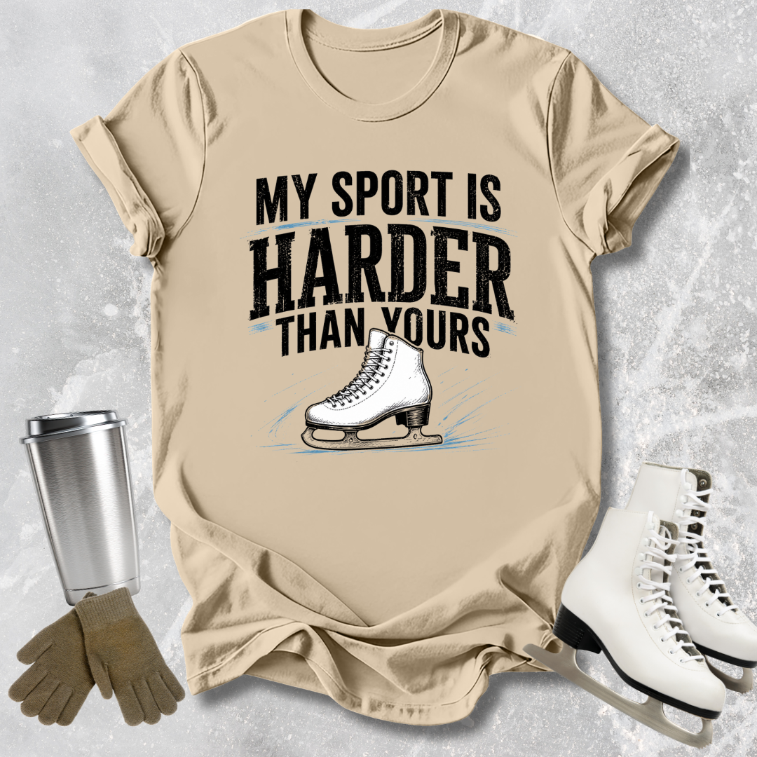 Beige t-shirt with ice skate graphic and text 'My sport is harder than yours' on a textured surface.