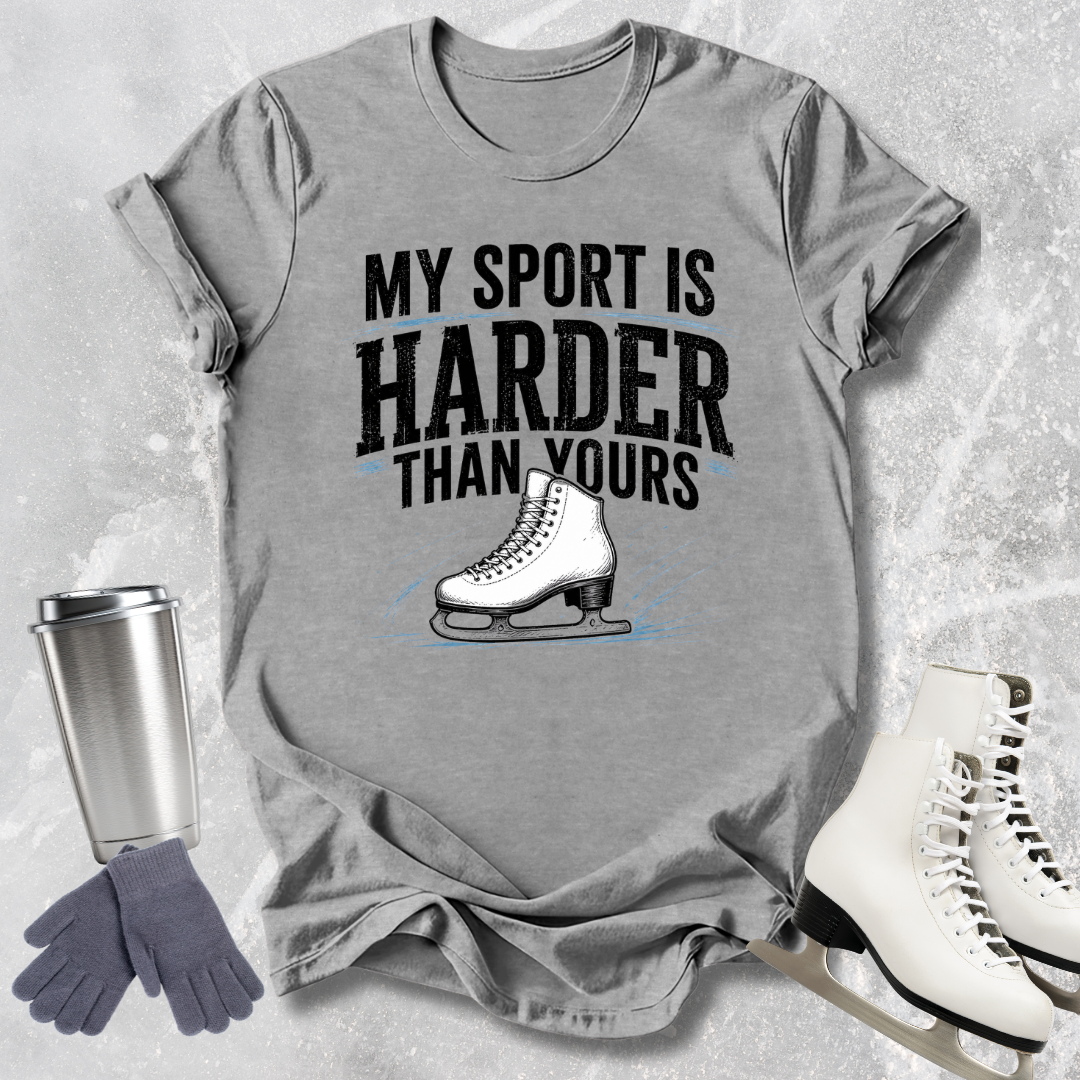 Gray t-shirt with 'My sport is harder than yours' text and ice skate graphic, surrounded by ice skates and a tumbler.
