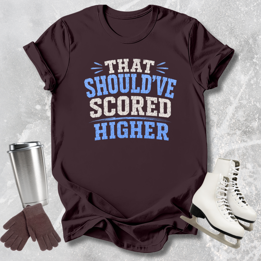Brown t-shirt with humorous text, silver tumbler, brown gloves, and white skates on a textured gray background