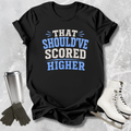 Black t-shirt with 'THAT SHOULD'VE SCORED HIGHER' text on a textured surface with accessories.