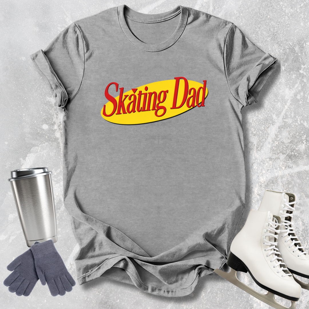 Gray t-shirt with 'Skating Dad' text, silver tumbler, gray gloves, and white skates on a textured gray background