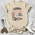 Beige t-shirt with coffee-themed graphic and text, placed on a textured surface with accessories like a tumbler and skates.