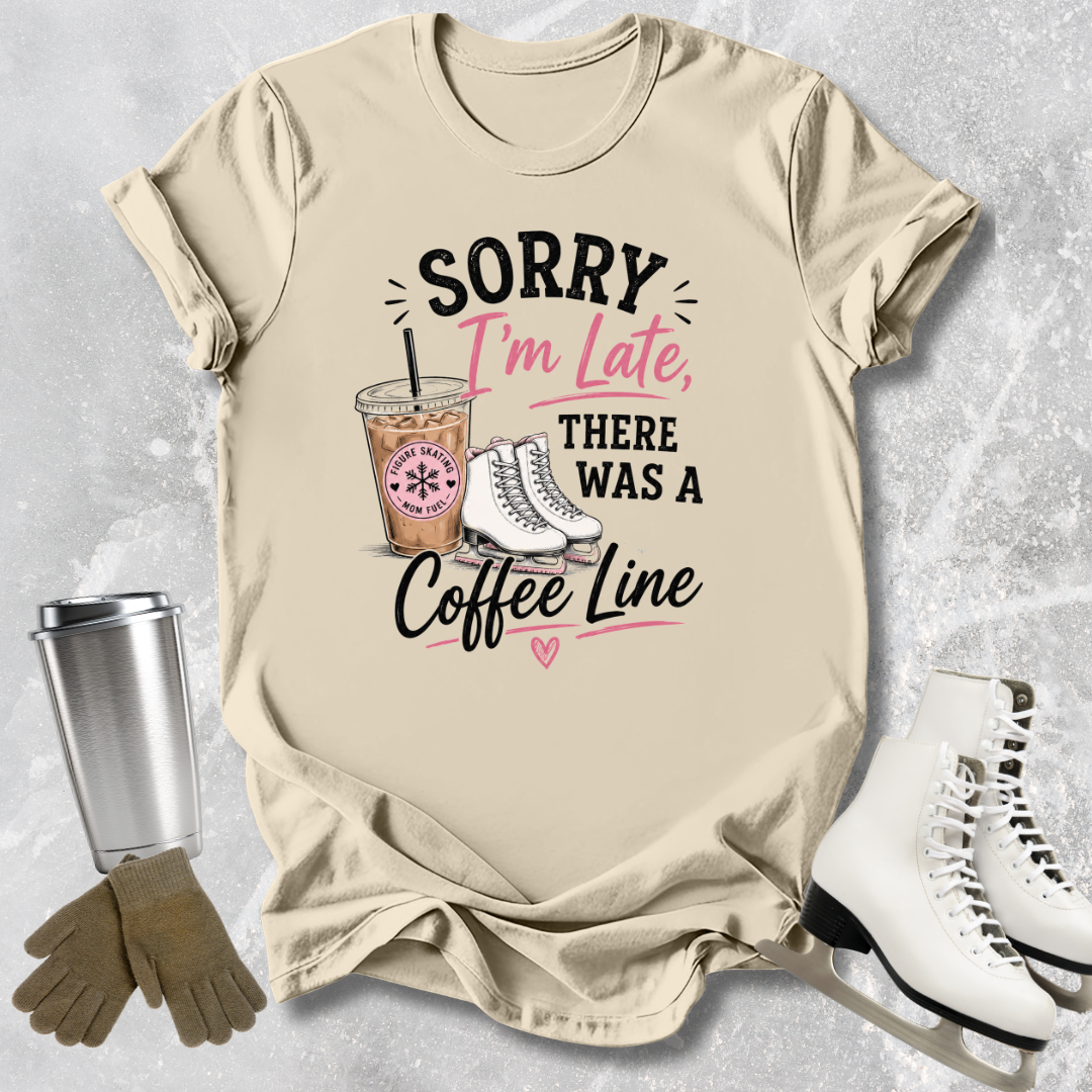 Beige t-shirt with coffee-themed graphic and text, placed on a textured surface with accessories like a tumbler and skates.