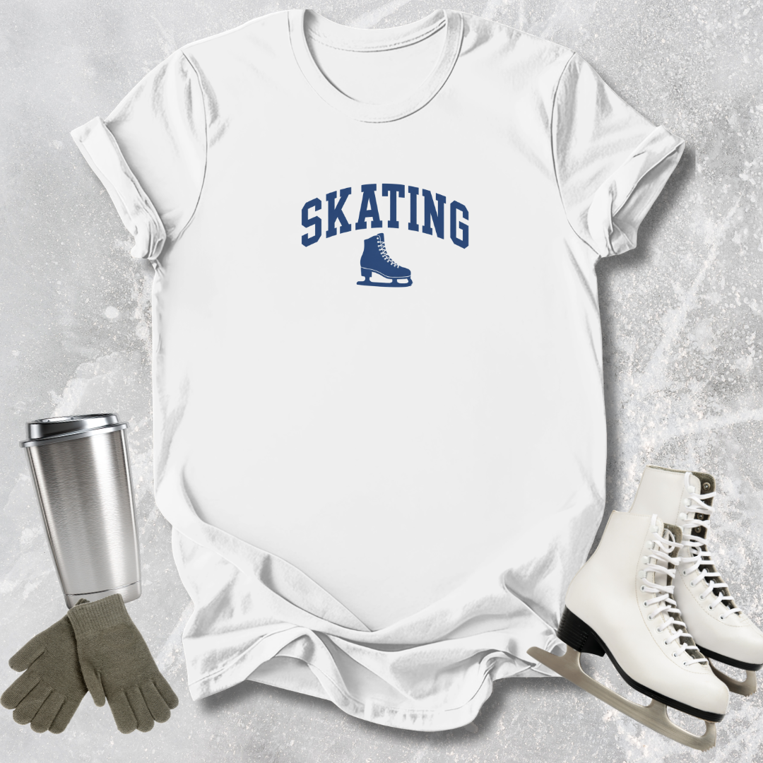 White t-shirt with 'SKATING' print, silver tumbler, gray gloves, and white skates on a textured surface.