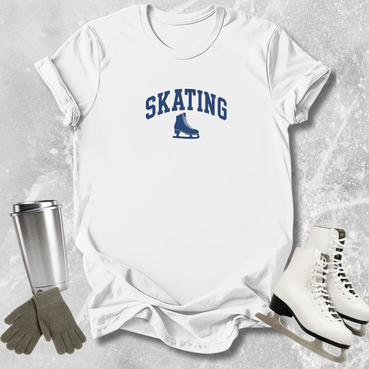 White t-shirt with 'SKATING' print, silver tumbler, gray gloves, and white skates on a textured surface.