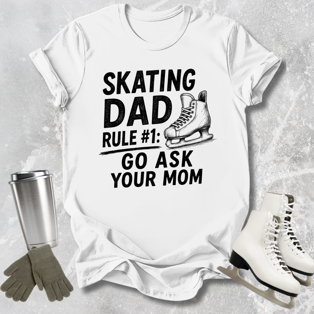 White t-shirt with 'Skating Dad' text, ice skates, gloves, and a tumbler on a gray background
